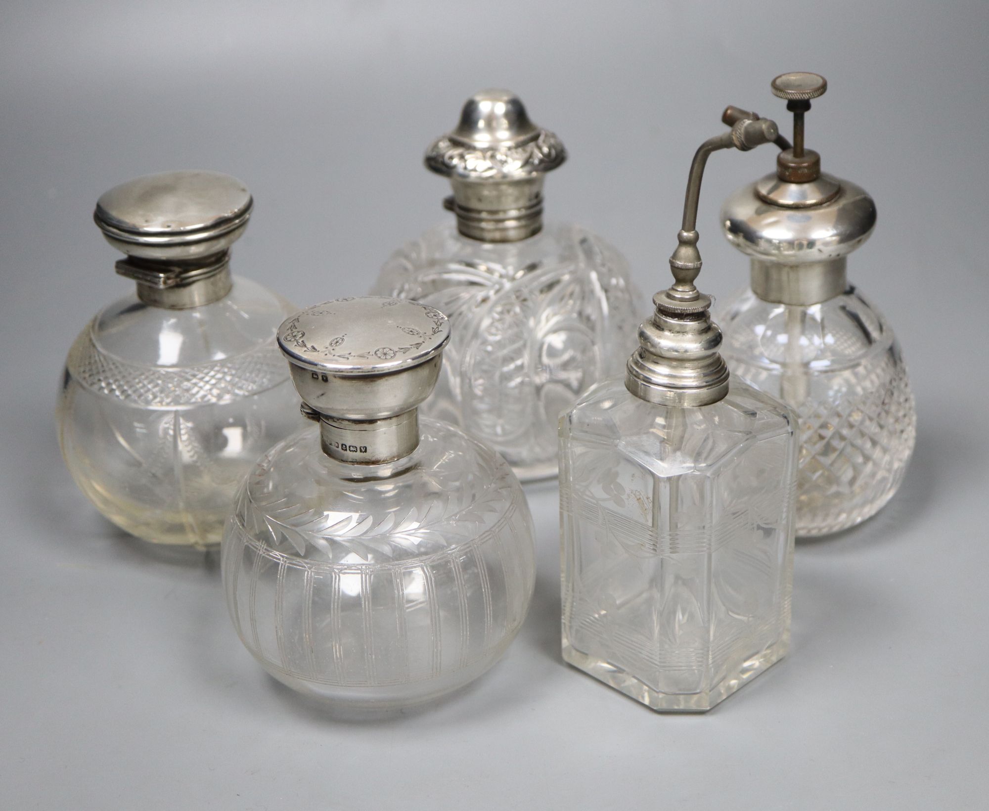 Two silver mounted glass atomisers and three silver mounted glass scent bottles, tallest overall 16cm.